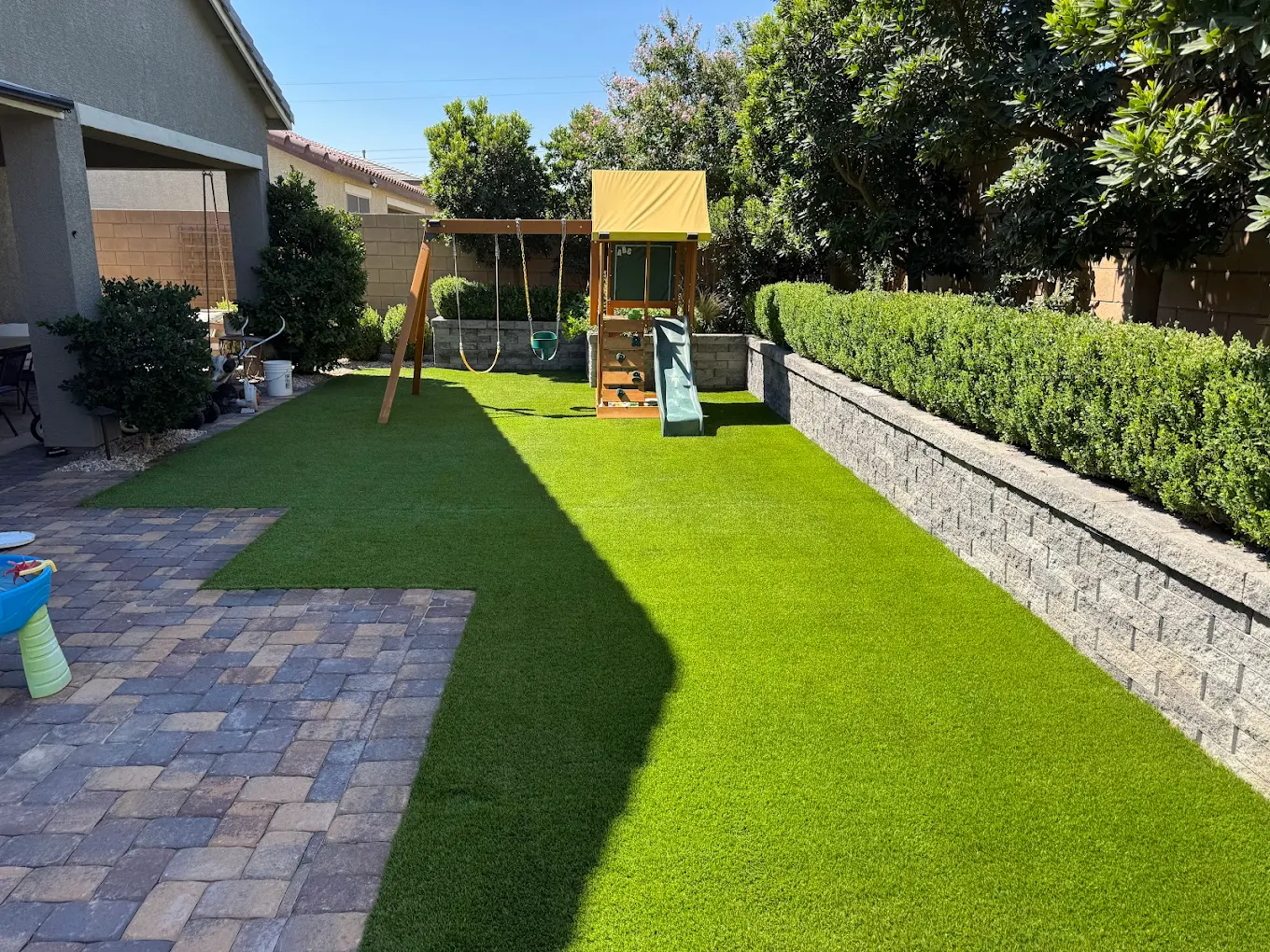 A pet-friendly San Diego backyard with artificial turf, pavers, and play area